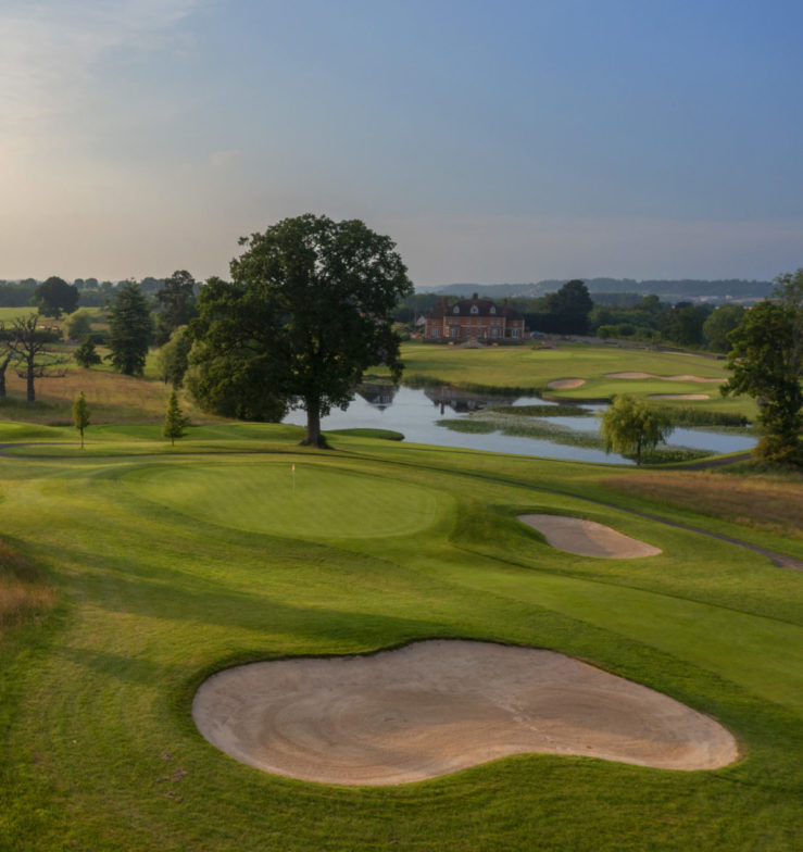 The 17th hole at The Astbury golf course, featuring a scenic landscape with rolling greens, water hazards, and tree-lined fairways.